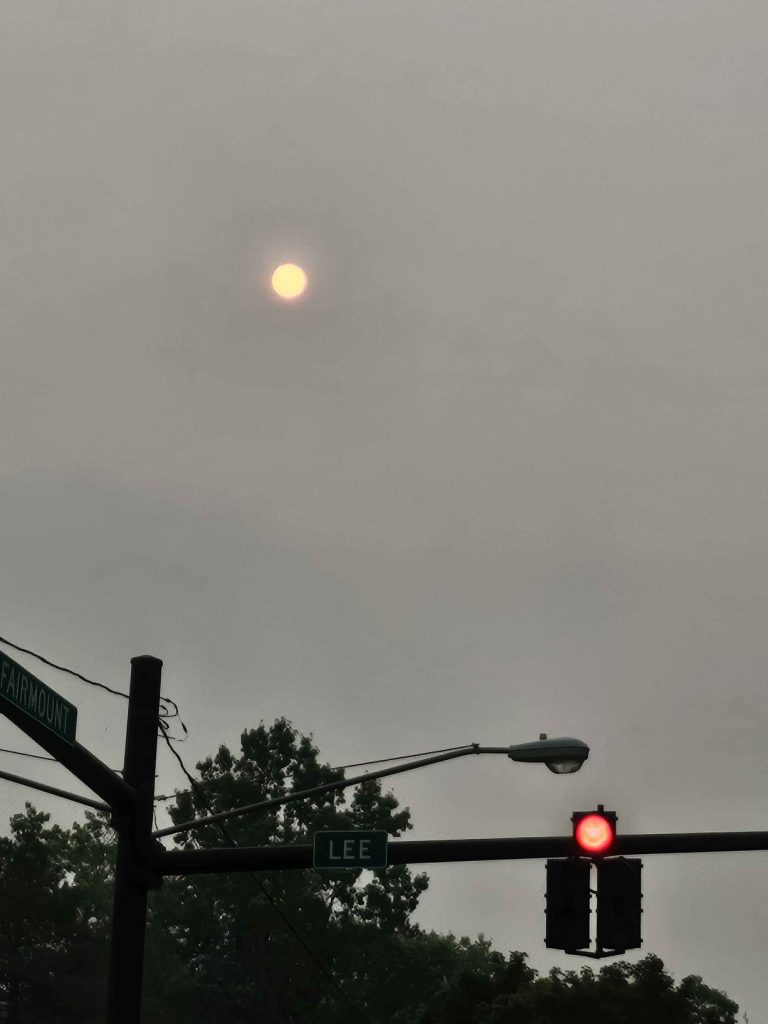 A dim orange sun over Cleveland streets through heavy Canadian wildfire smoke.